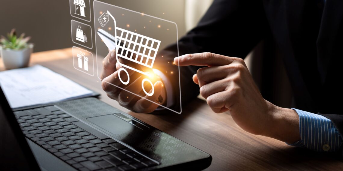 Individual using a digital shopping cart interface on a laptop with icons representing e-commerce.