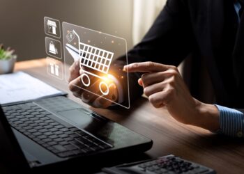 Individual using a digital shopping cart interface on a laptop with icons representing e-commerce.