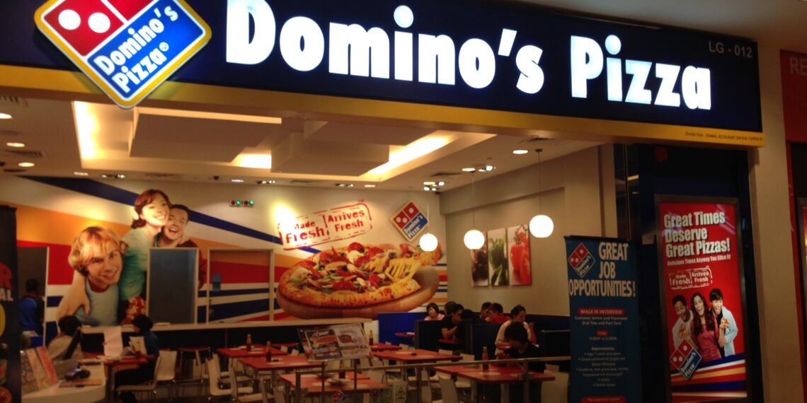 Entrance of a Domino's Pizza restaurant with signage and seating area visible.
