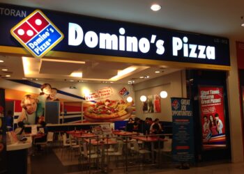 Entrance of a Domino's Pizza restaurant with signage and seating area visible.