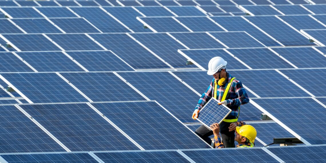 Two electricians working on solar panels in a solar energy installation site.