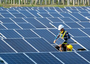 Two electricians working on solar panels in a solar energy installation site.