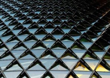 Close-up view of a modern building facade featuring a pattern of triangular glass panels.