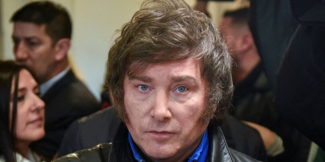 A man with dark, wavy hair and blue eyes wearing a black leather jacket.