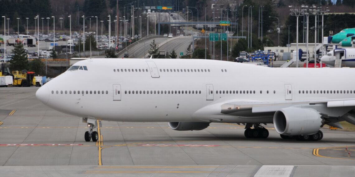 Boeing 747 aircraft taxiing on the runway at an airport with a clear sky in the background.