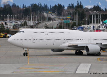 Boeing 747 aircraft taxiing on the runway at an airport with a clear sky in the background.