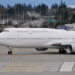 Boeing 747 aircraft taxiing on the runway at an airport with a clear sky in the background.