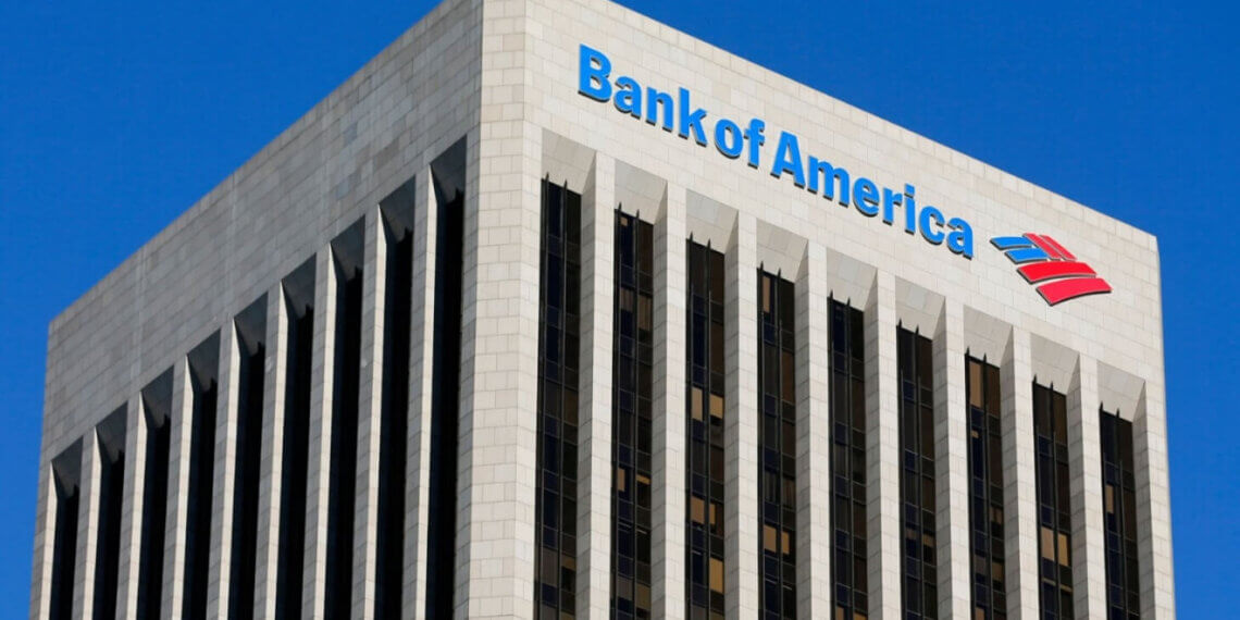 Bank of America logo displayed on the top of a tall building with a blue sky background.