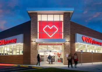 Exterior view of a CVS Pharmacy store with a prominent heart logo and illuminated signage at dusk.