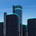 The General Motors Renaissance Center, featuring modern architecture and illuminated edges, against a blue sky.