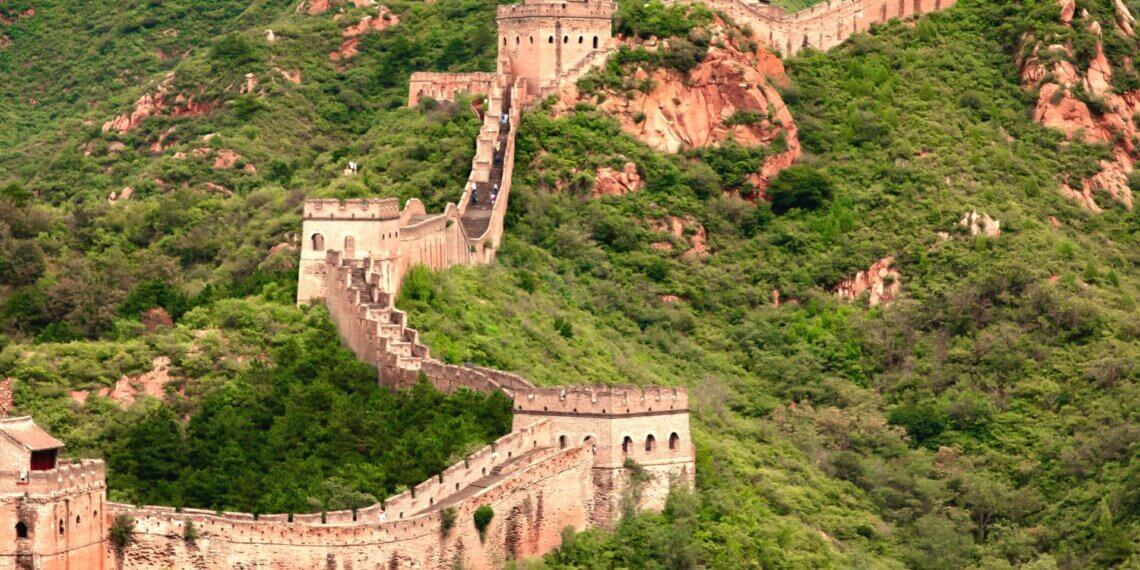 The Great Wall of China winding through a mountainous area covered in greenery.