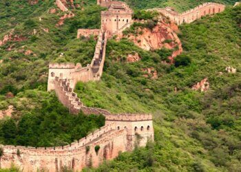 The Great Wall of China winding through a mountainous area covered in greenery.