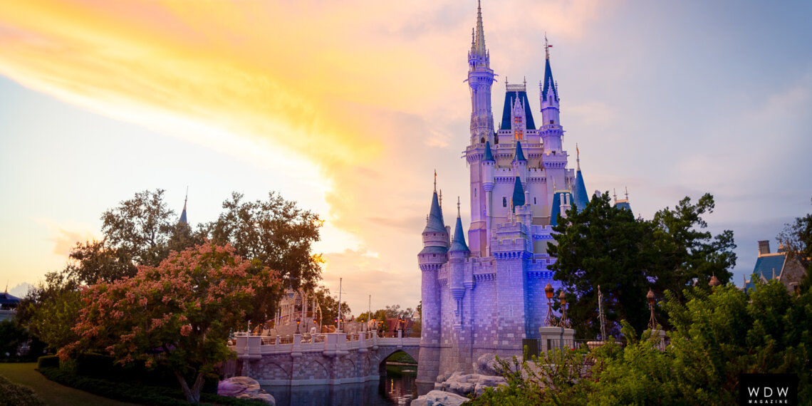 Cinderella Castle illuminated at sunset with a colorful sky in the background.