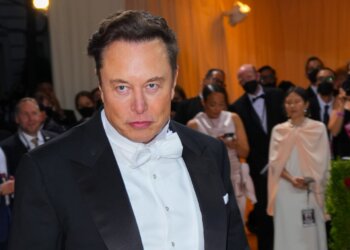 Elon Musk wearing a tuxedo with a bow tie at a formal event, looking directly at the camera.