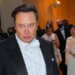 Elon Musk wearing a tuxedo with a bow tie at a formal event, looking directly at the camera.