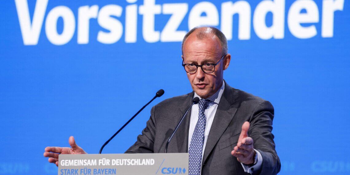 Friedrich Merz delivering a speech at the CSU party conference with a blue background.