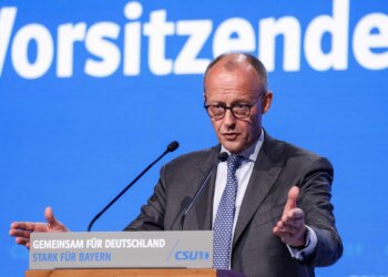 Friedrich Merz delivering a speech at the CSU party conference with a blue background.