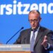 Friedrich Merz delivering a speech at the CSU party conference with a blue background.