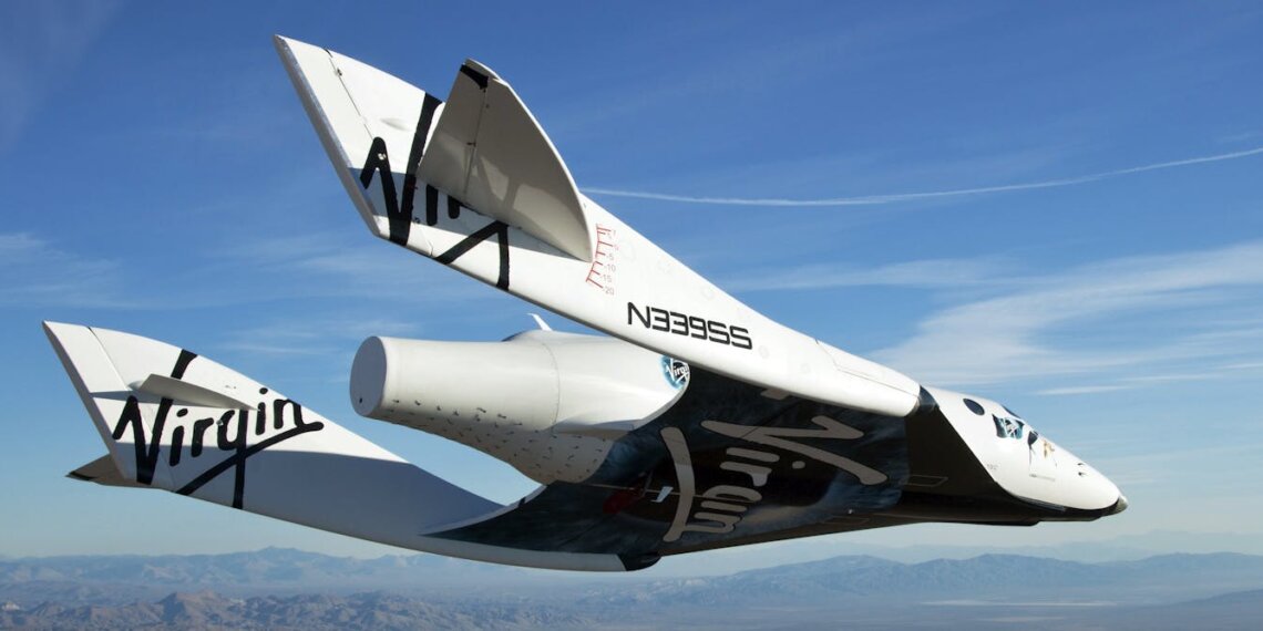 Virgin Galactic spacecraft flying in the sky with a clear blue background and mountains below.