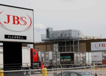 JBS Plainwell facility sign with trucks parked outside the building.