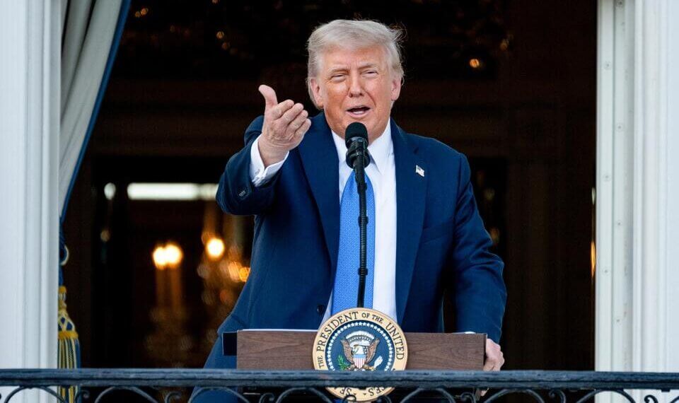 Man in a suit speaking at a podium with the Presidential seal in a formal setting.