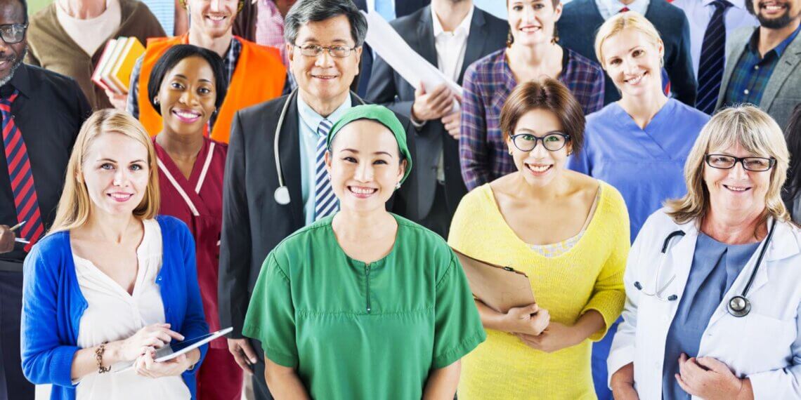 A diverse group of professionals, including healthcare workers and business people, posing for a photo.