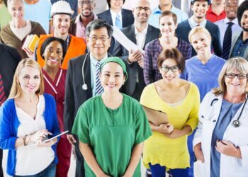 A diverse group of professionals, including healthcare workers and business people, posing for a photo.