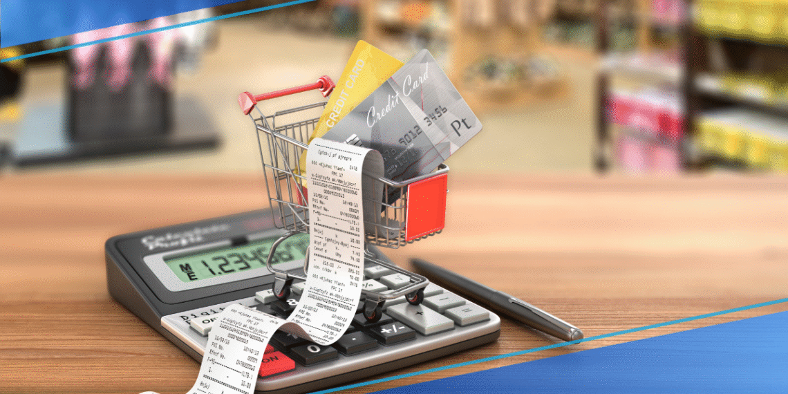 A shopping cart filled with receipts and credit cards placed on a calculator.