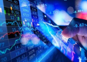 A hand pointing at a digital stock market data display with graphs and numbers.