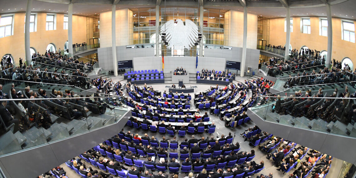 Interior view of the German Bundestag Plenary Hall with seating and a central stage.