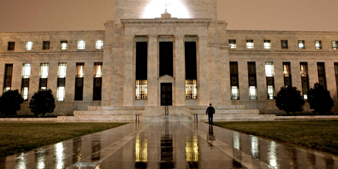 Exterior view of the Federal Reserve building illuminated at night with a flag on top.