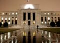Exterior view of the Federal Reserve building illuminated at night with a flag on top.