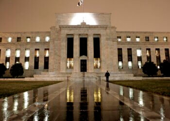 Exterior view of the Federal Reserve building illuminated at night with a flag on top.