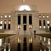 Exterior view of the Federal Reserve building illuminated at night with a flag on top.