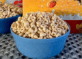 A blue bowl filled with Honey Nut Cheerios cereal on a textured surface.