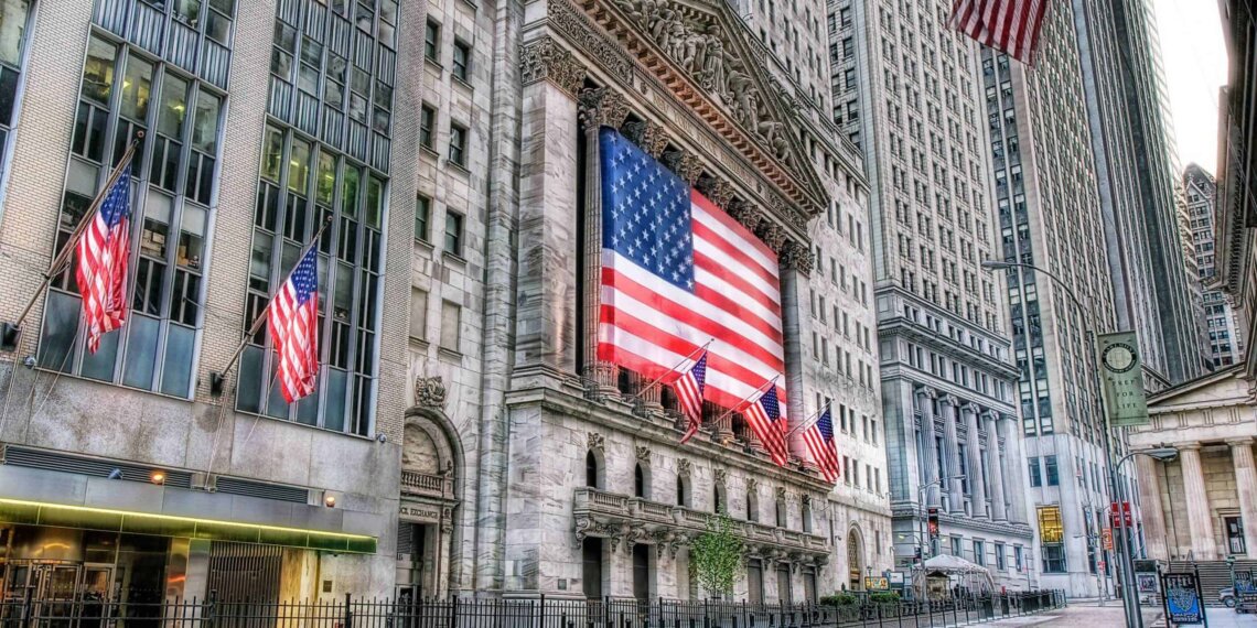 Facade of the New York Stock Exchange building featuring a large American flag and multiple smaller flags.