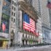 Facade of the New York Stock Exchange building featuring a large American flag and multiple smaller flags.