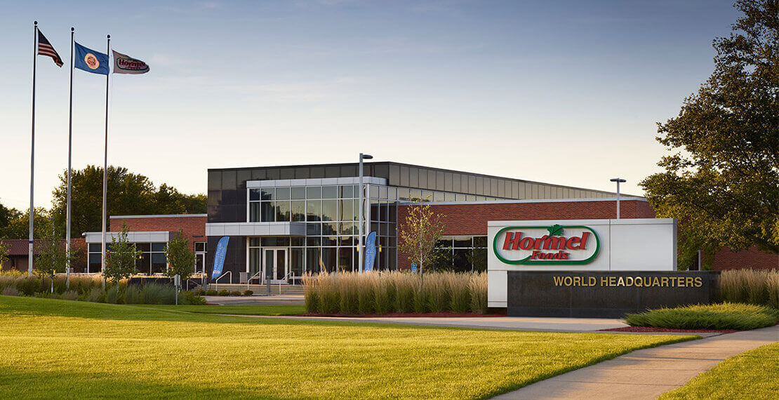 Exterior view of the Hormel Foods World Headquarters building with signage and flags.