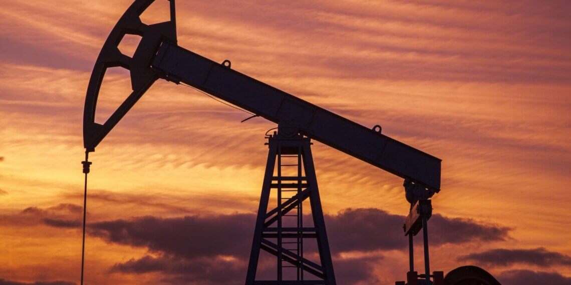 Silhouette of an oil jack pump against a colorful sunset sky.