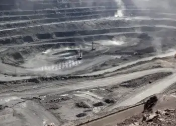 Aerial view of an open-pit mining site with machinery and layered earth formations.