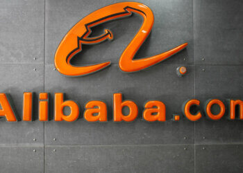 Orange Alibaba.com logo displayed on a gray wall with a modern design.