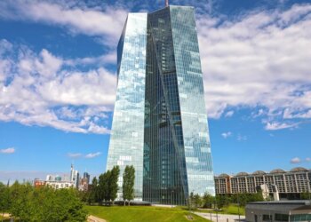 Modern glass building of the European Central Bank in Frankfurt, Germany, under a blue sky with clouds.