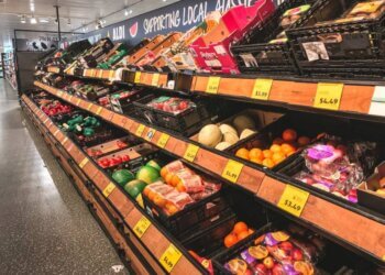 Produce section in a grocery store featuring various fruits and vegetables in display bins.