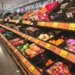 Produce section in a grocery store featuring various fruits and vegetables in display bins.