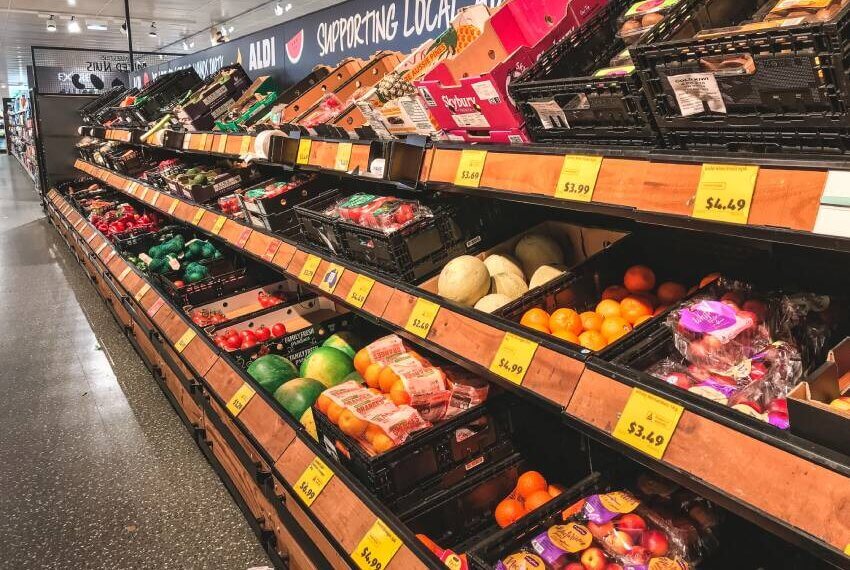 Produce section in a grocery store featuring various fruits and vegetables in display bins.