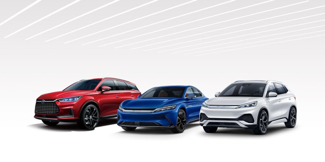 Three electric vehicles: a red SUV, a blue sedan, and a white crossover, displayed in a row.