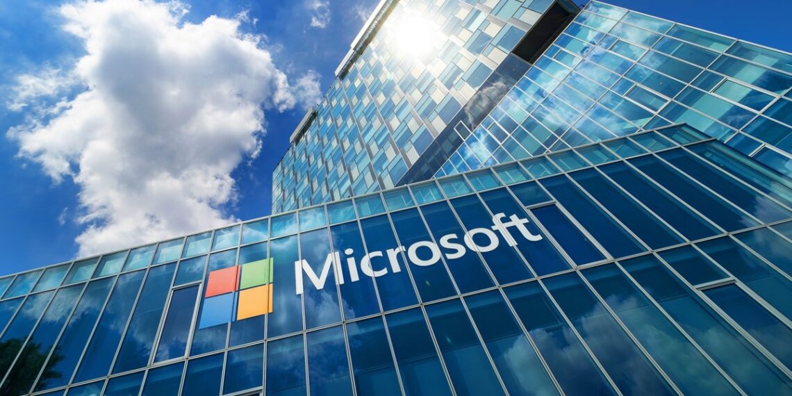 Microsoft office building with a glass facade reflecting the sky and clouds.