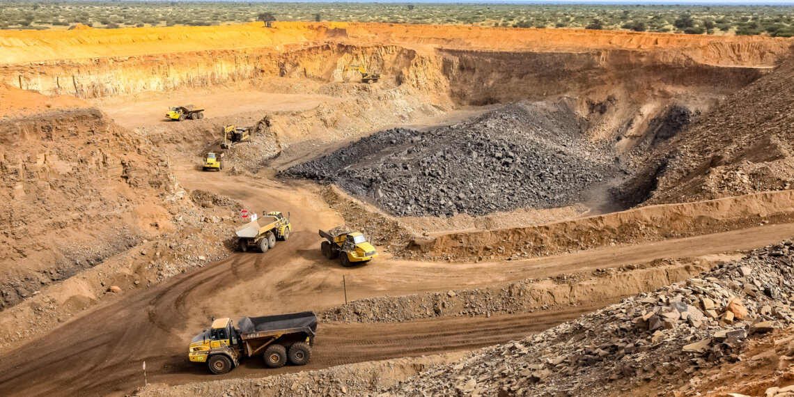 Open-pit mining site featuring multiple heavy trucks and excavated earth in a large quarry.