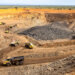 Open-pit mining site featuring multiple heavy trucks and excavated earth in a large quarry.