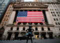 New York Stock Exchange building featuring a large American flag and a bronze statue of a girl in front.